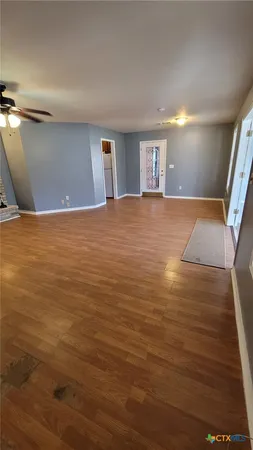 an empty room with wooden floor fireplace and windows