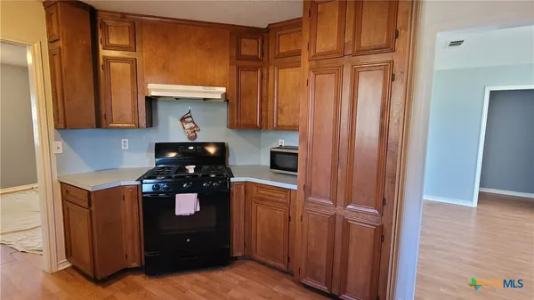 a kitchen with stainless steel appliances a refrigerator a sink a stove wooden floor and cabinets