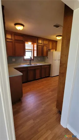 an empty room with wooden floor chandelier and windows