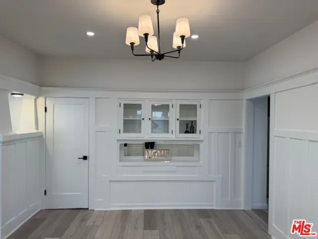 a view of a hallway with wooden floor and chandelier