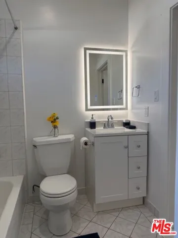 a bathroom with a granite countertop toilet sink and mirror