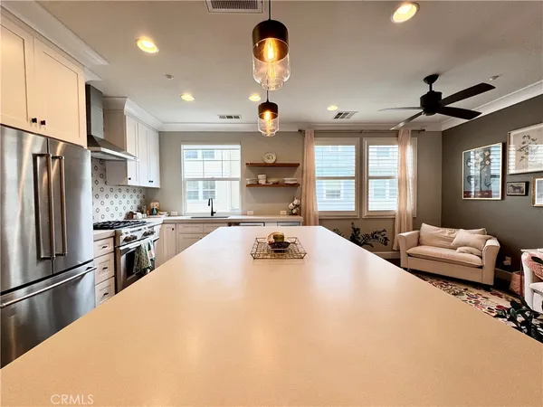 a large kitchen with stainless steel appliances a stove a refrigerator a sink a dining table and chairs with wooden floor