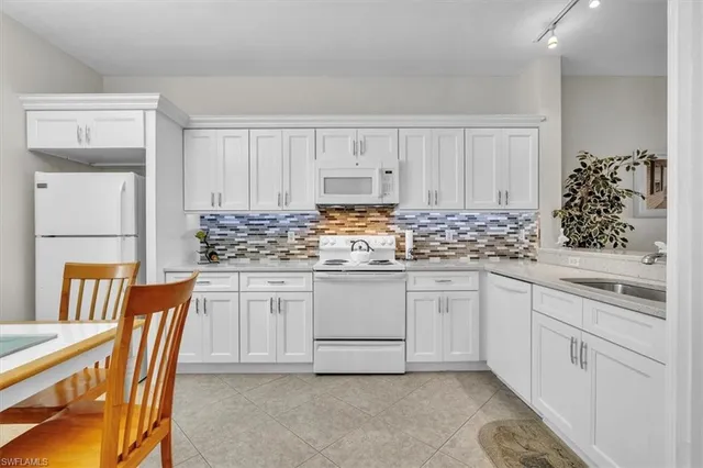 a kitchen with granite countertop white cabinets and white appliances