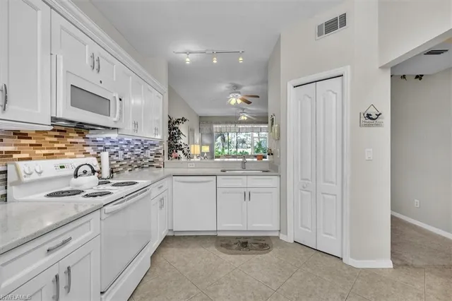 a kitchen with white cabinets sink and appliances