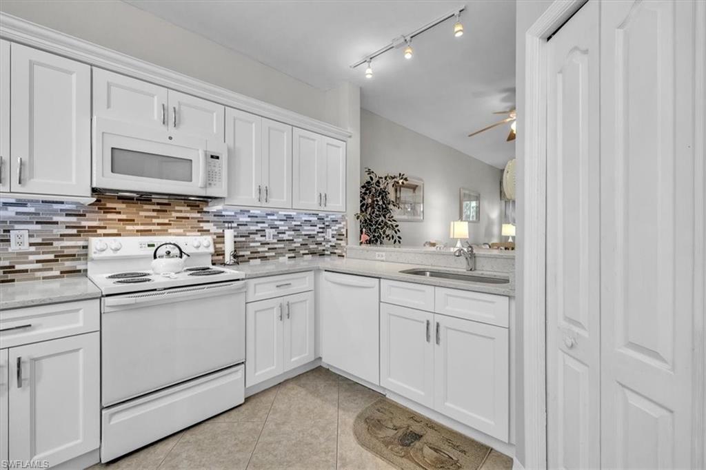 8075 Tiger Cove, Unit 1706 Naples, FL 34113 - Photo 10 of 50 a kitchen with white cabinets sink and stove