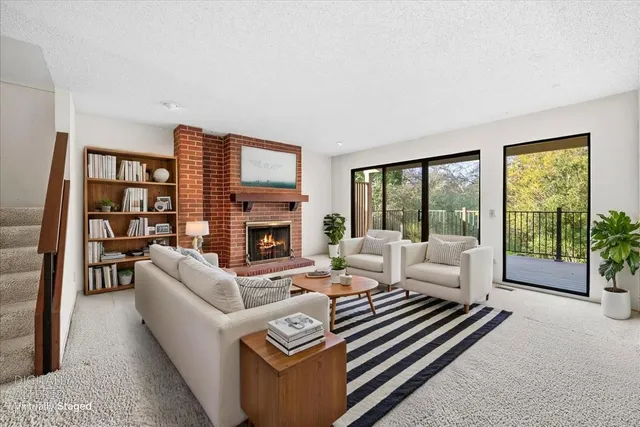 a living room with furniture a large window and a fireplace