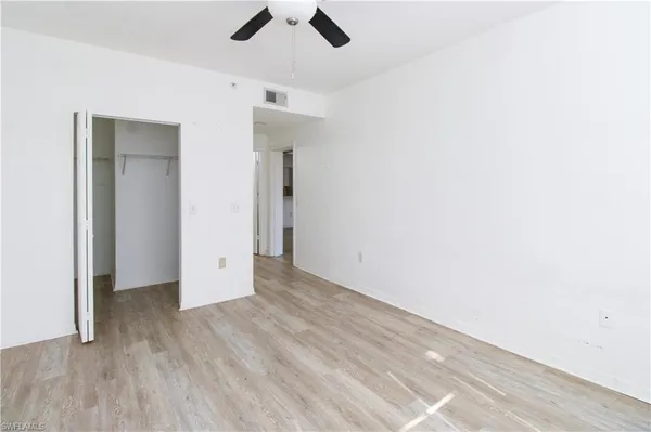 an empty room with ceiling fan and window