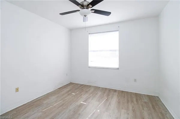 an empty room with a window and a ceiling fan