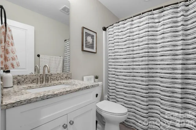 a bathroom with a granite countertop toilet and sink