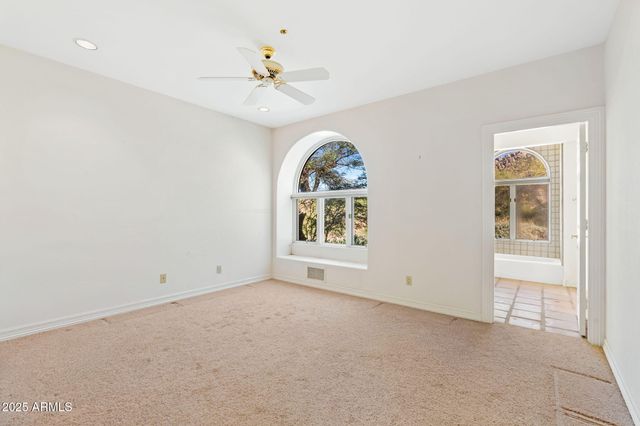 an empty room with windows and chandelier fan