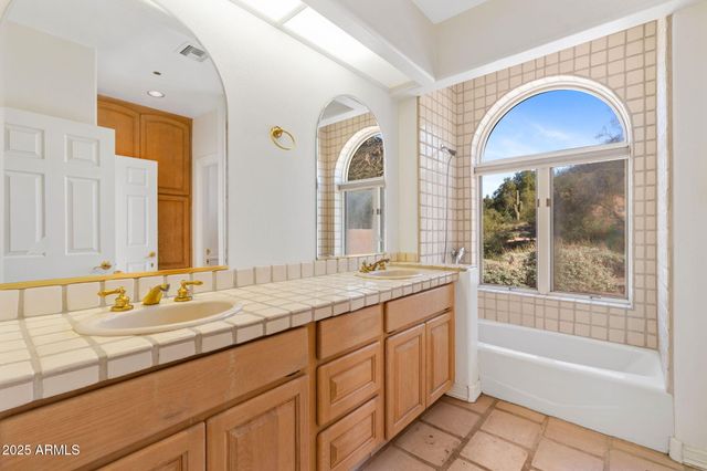 a bathroom with a granite countertop tub a double vanity sink and a large mirror