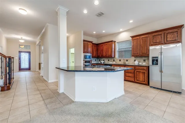 a kitchen with stainless steel appliances granite countertop a refrigerator a sink a stove top oven and a refrigerator