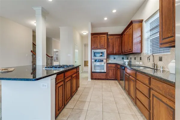 a large kitchen with stainless steel appliances granite countertop a large stove top oven a sink a dining table and chairs