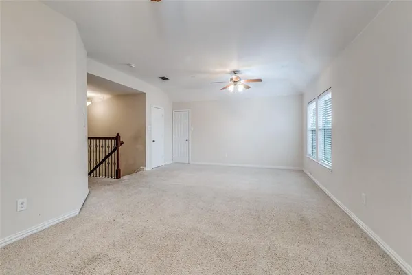 a view of an empty room and a chandelier fan