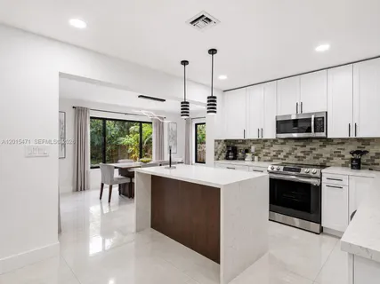 a kitchen with a stove a sink a microwave a dining table and chairs