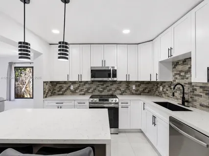 a kitchen with stainless steel appliances granite countertop a sink a stove and a refrigerator