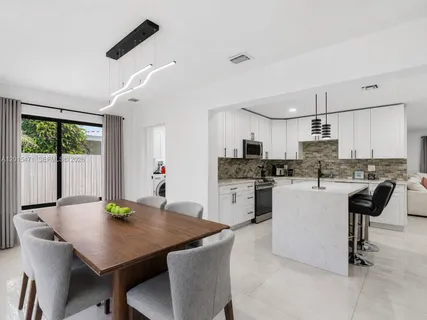 a kitchen with kitchen island a dining table and chairs