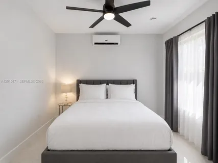 a large bed sitting in a bedroom next to a window and a chandelier