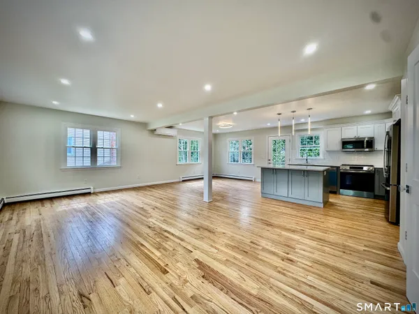 a view of a kitchen and an empty room with wooden floor