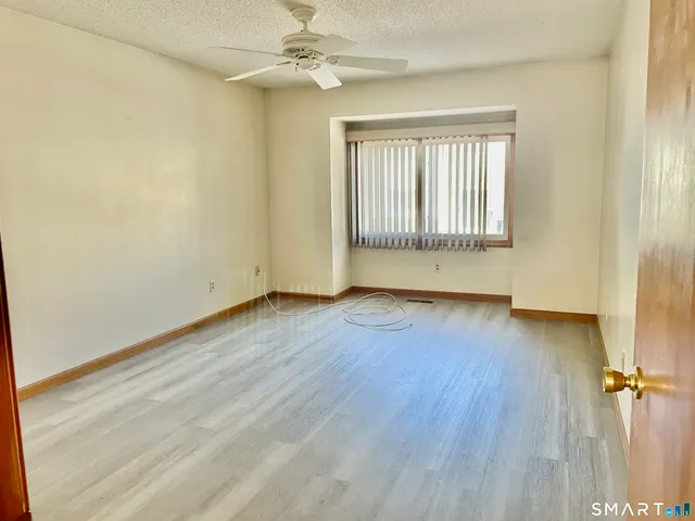 an empty room with wooden floor fan and windows