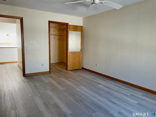 an empty room with wooden floor and a ceiling fan