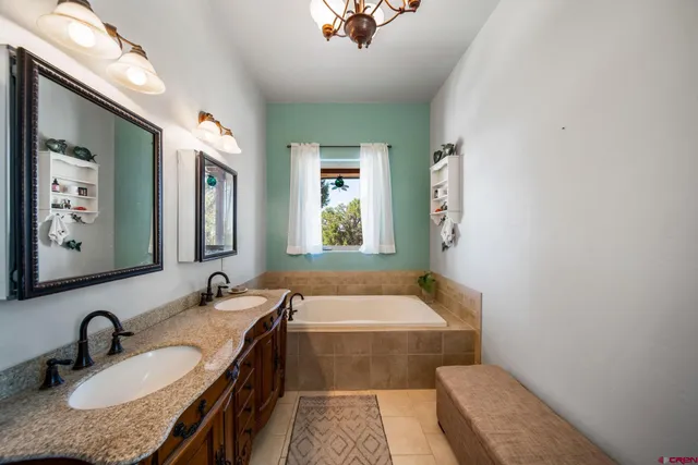 a bathroom with a granite countertop tub sink and mirror