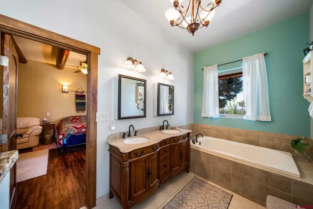 a spacious bathroom with a tub double sink and two mirror