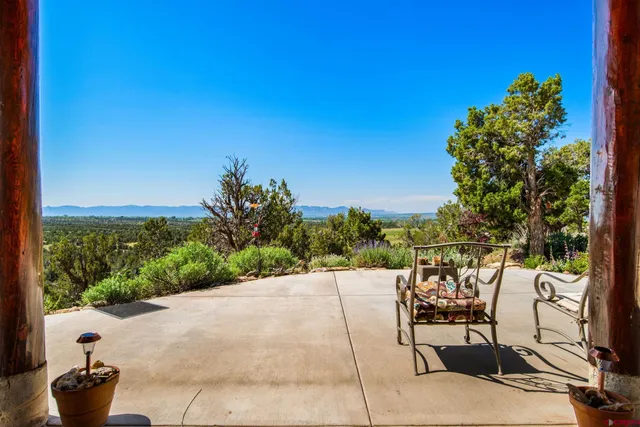 a view of a patio with a table and chairs under an umbrella next to a yard