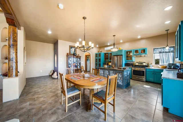 a dining hall with stainless steel appliances kitchen island granite countertop a table and chairs