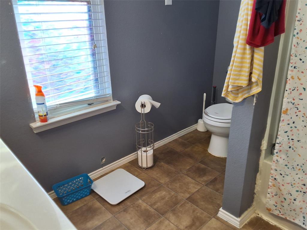 112 Hancock Street Venus, TX 76084 - Photo 23 of 25 Bathroom featuring a window with horizontal blinds, a white toilet, and brown-toned tile flooring