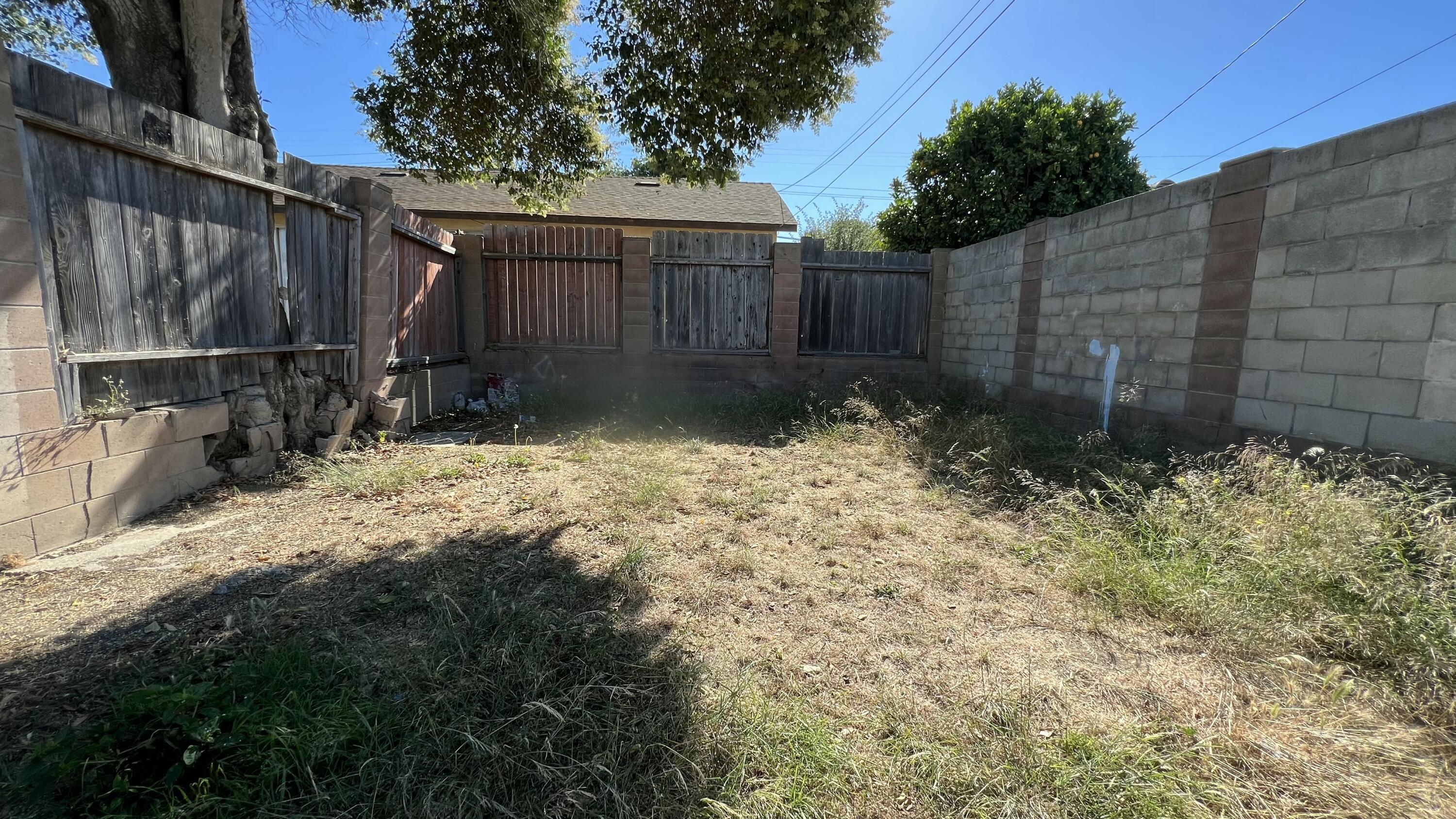 309 V Street Lompoc, CA 93436 - Photo 6 of 24 a view of backyard with wooden fence and a large tree