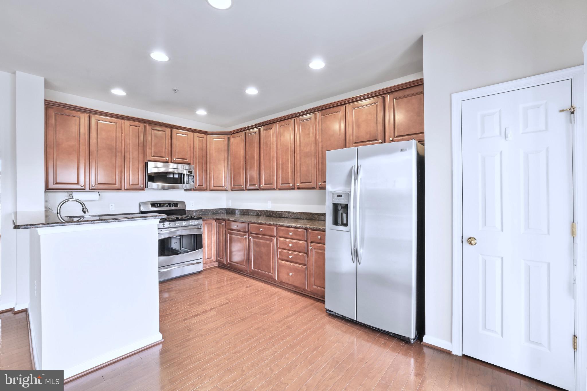 6055 Wicker Lane, Unit 128 Centreville, VA 20121 - Photo 15 of 36 a kitchen with granite countertop stainless steel appliances a refrigerator cabinets and wooden floor