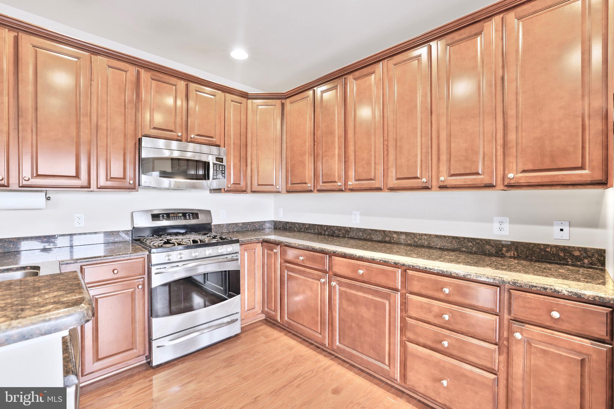 6055 Wicker Lane, Unit 128 Centreville, VA 20121 - Photo 7 of 36 a kitchen with granite countertop a stove top oven microwave and cabinets