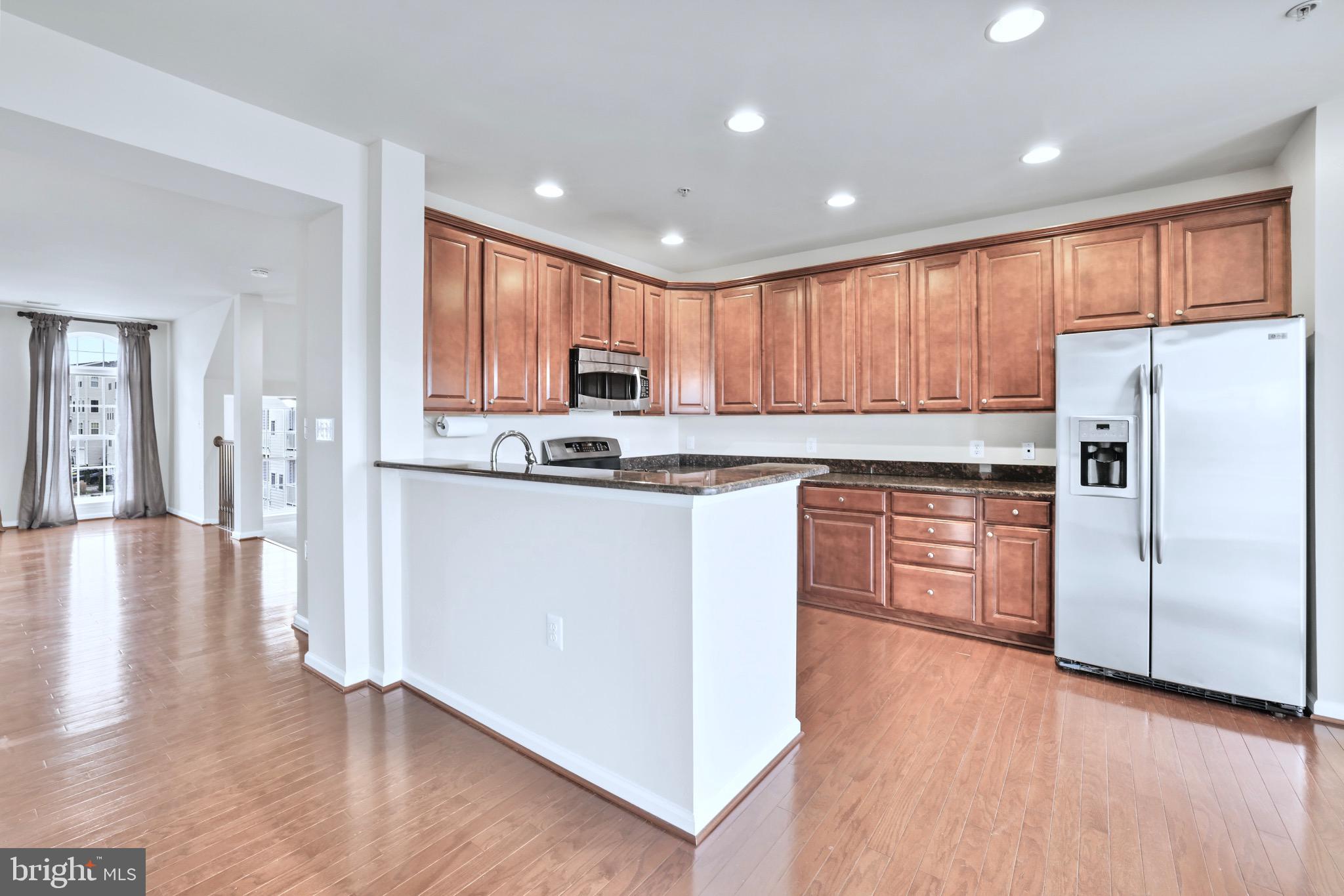 6055 Wicker Lane, Unit 128 Centreville, VA 20121 - Photo 10 of 36 a kitchen with stainless steel appliances granite countertop a refrigerator a stove top oven a sink and dishwasher with wooden floor