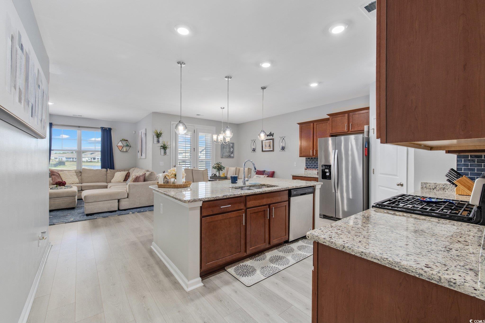 6009 Ranch View Drive Myrtle Beach, SC 29588 - Photo 4 of 40 Kitchen featuring a center island with sink, light wood-type flooring, light stone counters, stainless steel appliances, and a sink