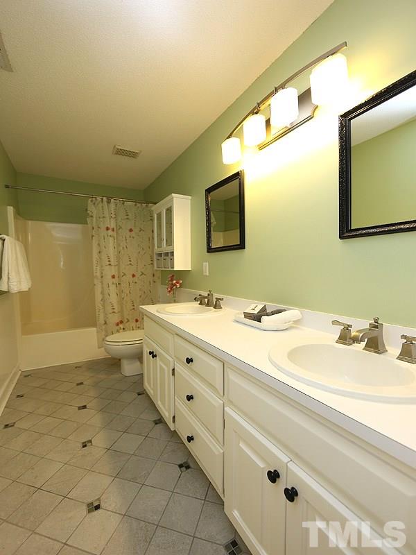 6825 Pinnacle Ridge Road Raleigh, NC 27603 - Photo 19 of 23 a bathroom with a double vanity sink a mirror and a bathtub
