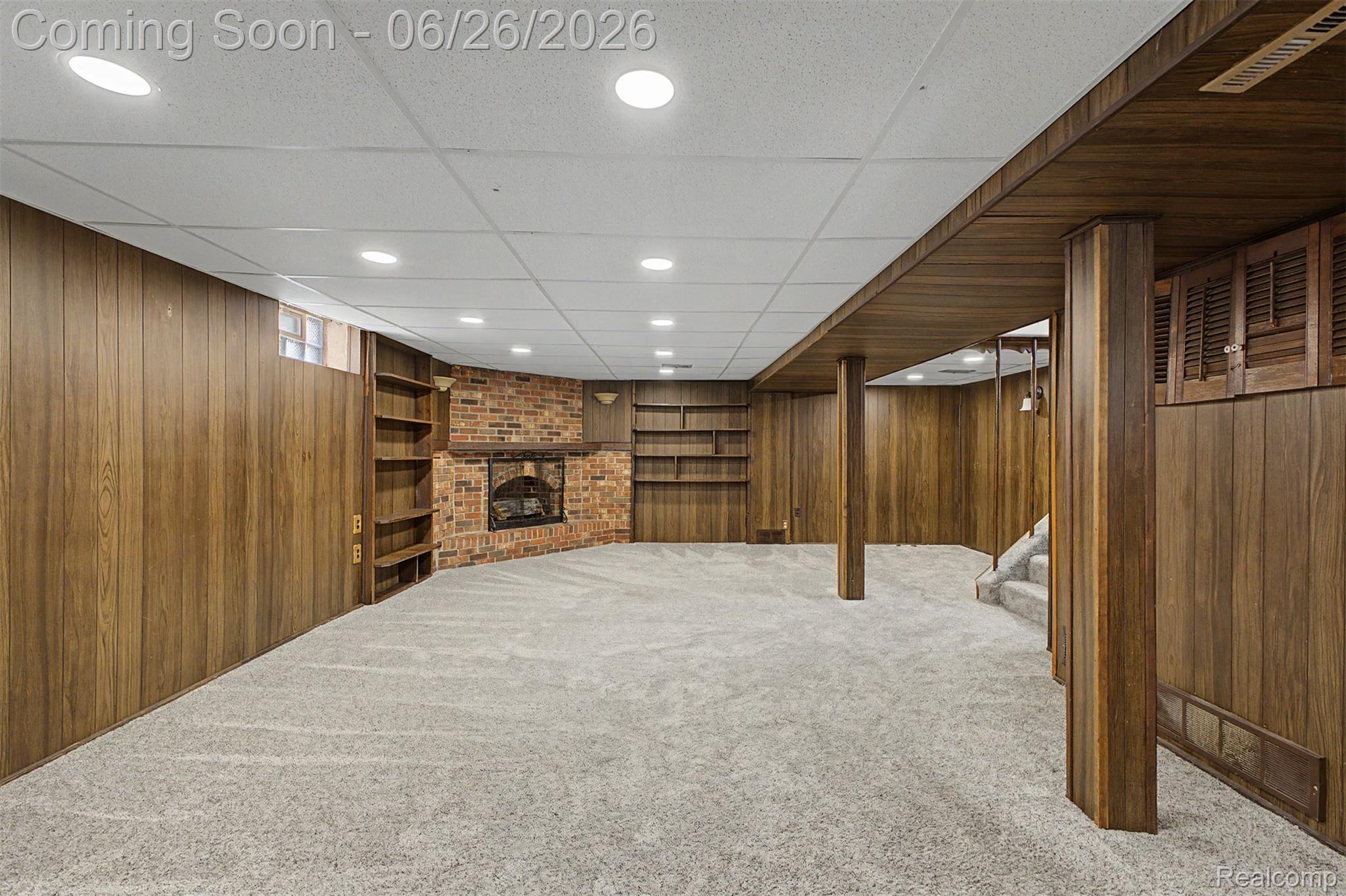 2216 Banner Street Dearborn, MI 48124 - Photo 24 of 34 Expansive recreation room featuring wood-panel walls, a brick fireplace with a wood mantel, built-in shelving, recessed ceiling lighting, and carpet flooring