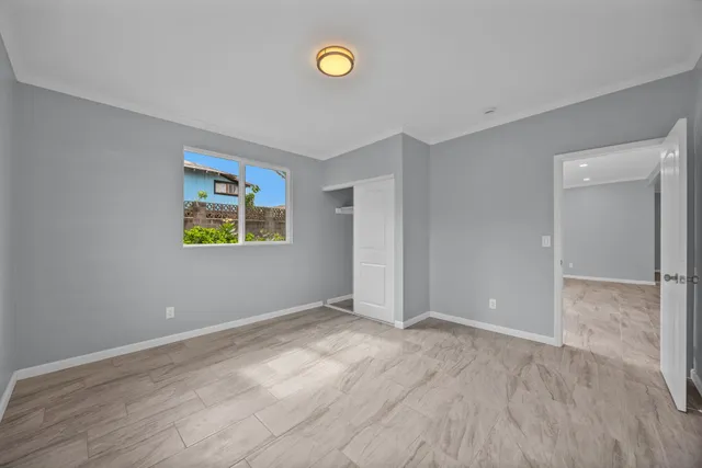 a view of an empty room with window and wooden floor