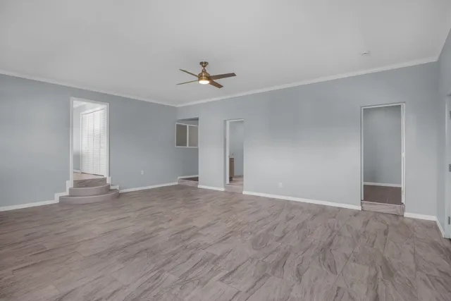 a view of an empty room with wooden floor and a ceiling fan