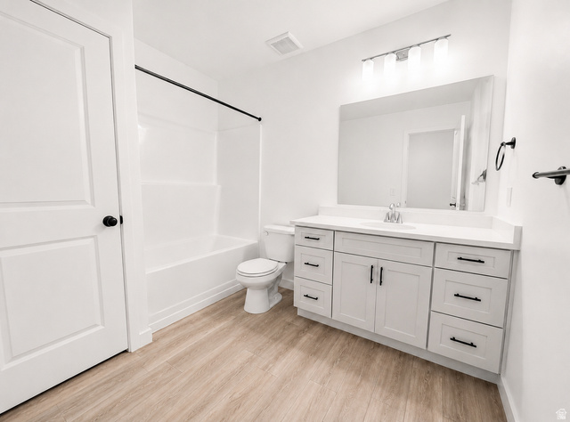 1004 West Paramount Cove South, Unit 315 Ogden, UT 84405 - Photo 32 of 42 Basement full bathroom featuring a white vanity with a quartz countertop and black hardware, a large mirror, and wood-finish flooring