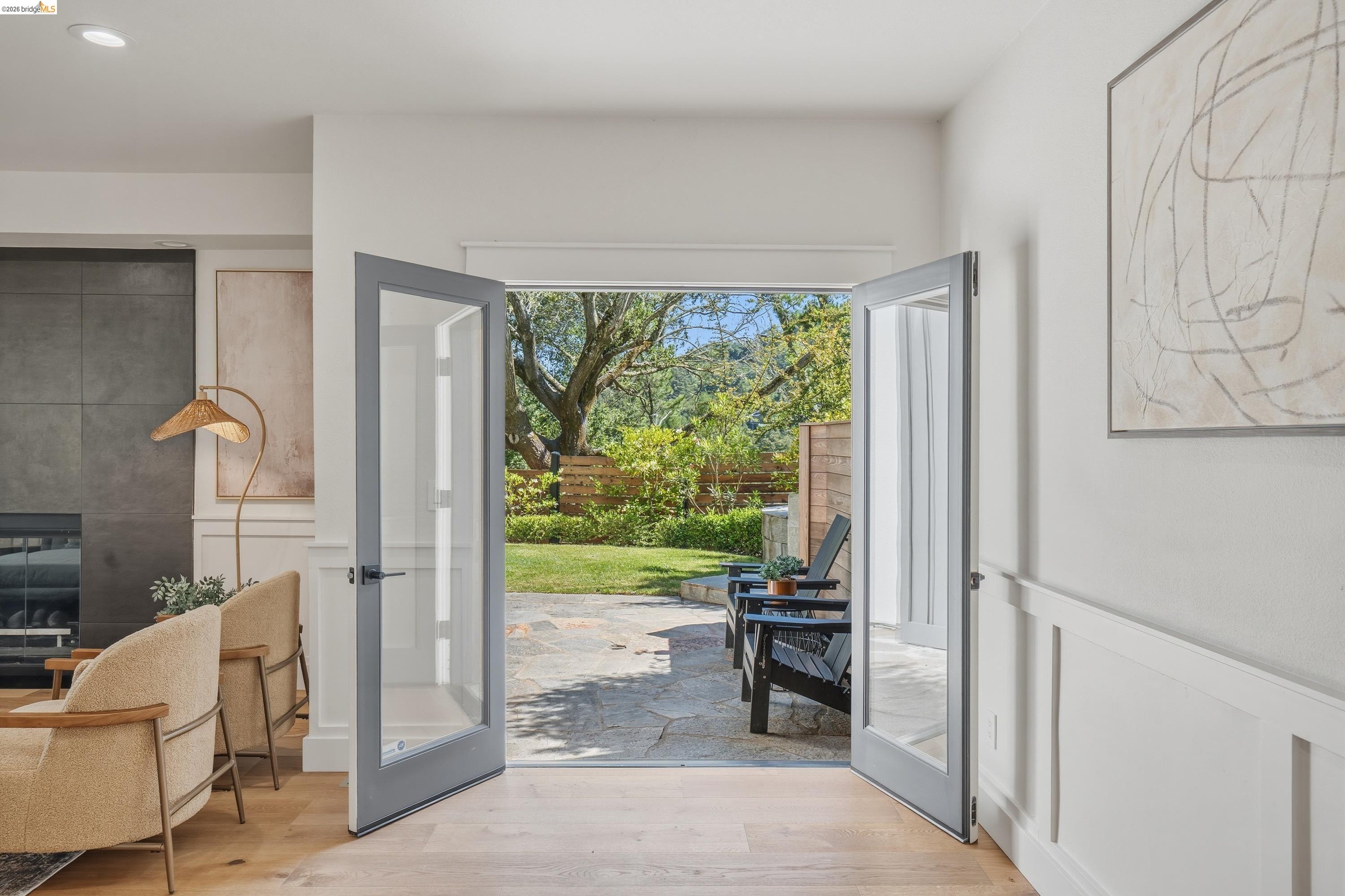 4120 Happy Valley Road Lafayette, CA 94549 - Photo 6 of 33 Glass-paneled French doors opening to an outdoor patio with stone pavers, bordered by a manicured lawn and mature trees