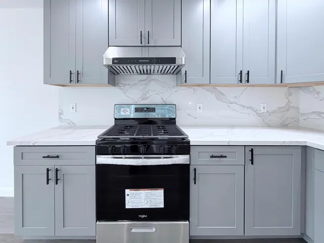 a kitchen with granite countertop white cabinets and a stove