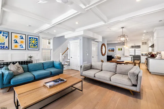 a living room with furniture kitchen view and a wooden floor