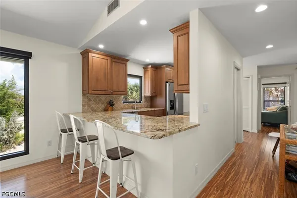 a view of a kitchen with kitchen island granite countertop wooden floor and stainless steel appliances