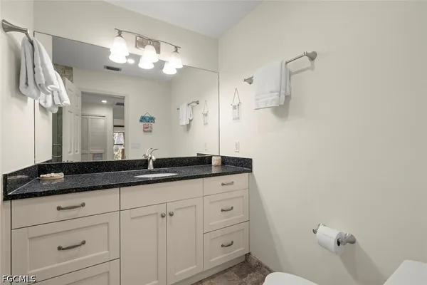 a bathroom with a granite countertop sink a toilet and mirror