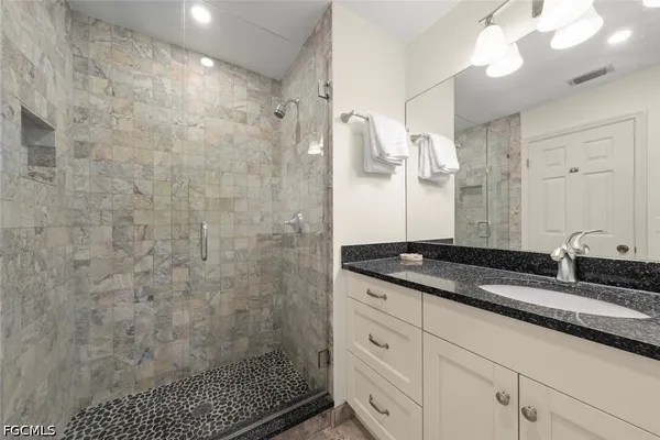 a bathroom with a granite countertop sink a mirror and shower
