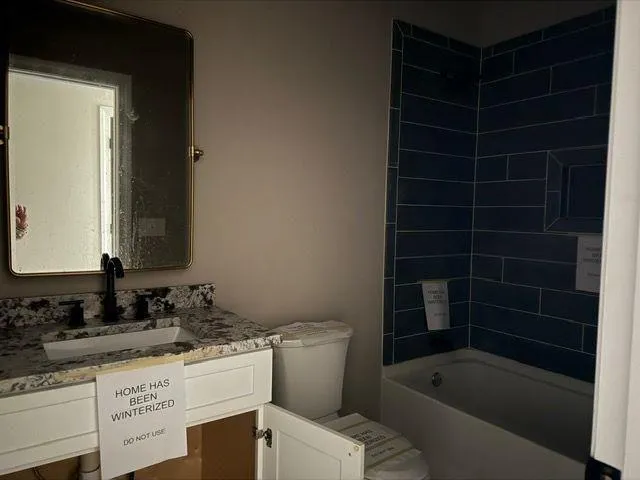 a bathroom with a granite countertop sink a toilet and bathtub