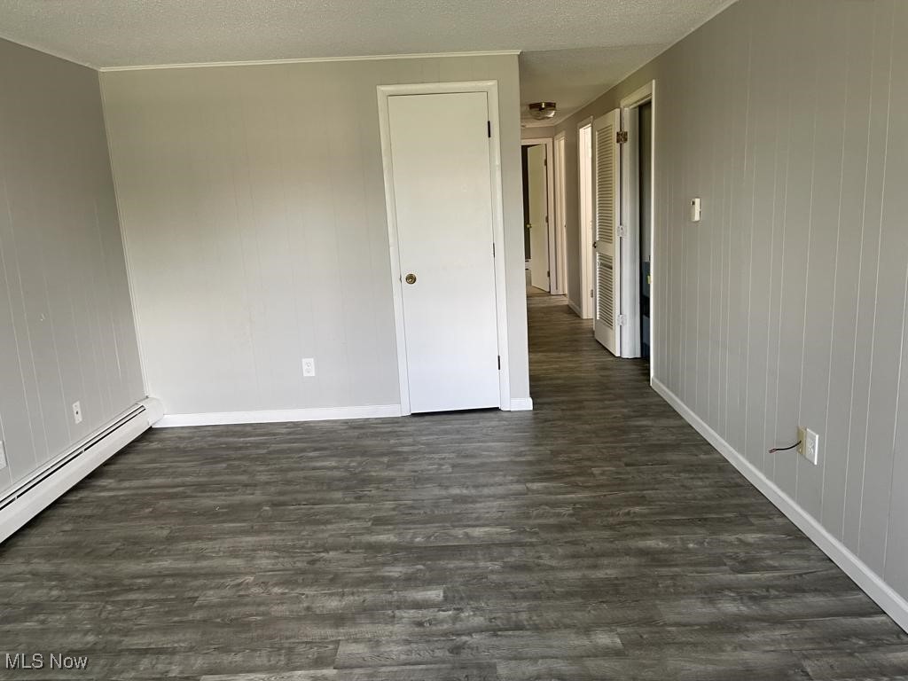715 South Abbe Road Elyria, OH 44035 - Photo 3 of 14 Unfurnished room with a textured ceiling, dark wood-type flooring, and a baseboard radiator