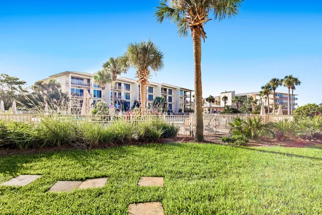 a front view of a house with a yard and palm trees