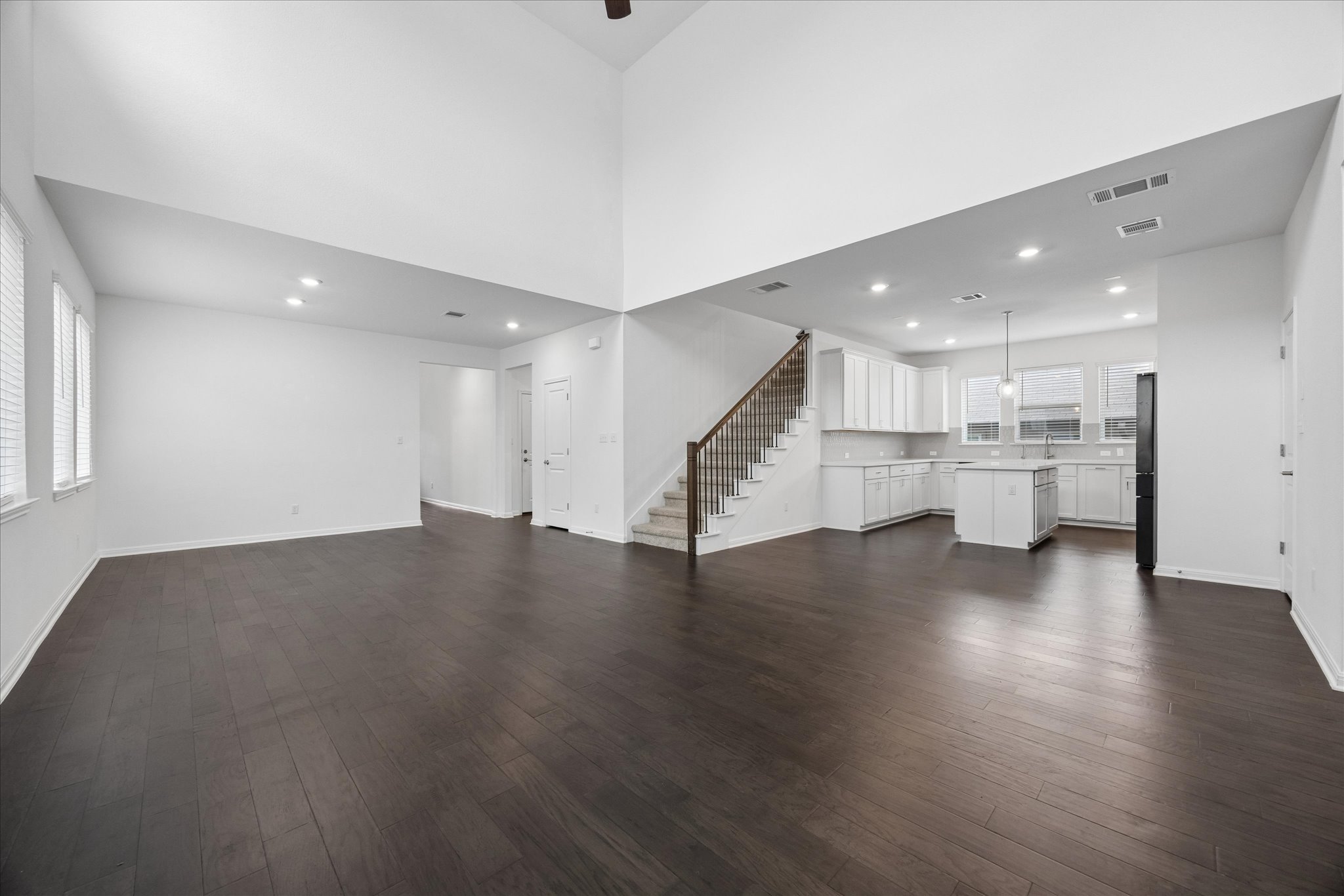 6407 Rounded Pebble Lane Buda, TX 78610 - Photo 5 of 32 An open-concept layout showcases dark hardwood flooring, a contemporary kitchen, and a dramatic vaulted ceiling.